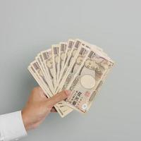 mão de homem segurando a pilha de notas de iene japonês. dinheiro de mil ienes. dinheiro do japão, impostos, economia de recessão, inflação, investimento, finanças e conceitos de pagamento de compras foto