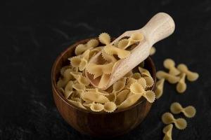 pilha de macarrão cru em uma tigela de madeira foto