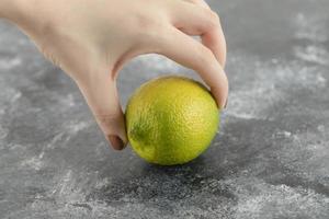 mão de uma mulher segurando um limão verde fresco foto