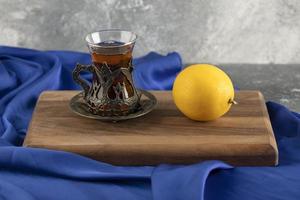 um copo de chá com limão em uma tábua de madeira