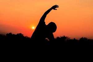 silhueta do masculino meditando e ioga praticando com exercício às nascer do sol dentro público parque manhã foto