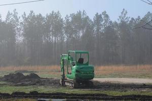 uma pequeno escavadora escavação uma Abandonar em uma construção local foto