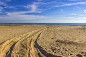 vestígios do carro pneus em a areia do a mar de praia. carro pneus impressões em mar areia durante a dia foto