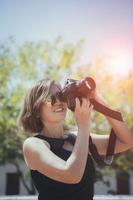 ásia mulher levando uma foto com dslr Câmera em pé ao ar livre contra lindo Sol luz