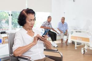 enfermagem casa Cuidado conceito. idosos mulher usando uma Móvel Telefone. olhando às Câmera foto