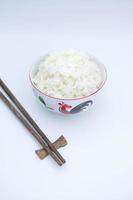 arroz dentro uma cerâmico tigela com de madeira pauzinho em branco fundo foto