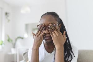 africano menina dentro óculos esfrega dela olhos, sofrimento a partir de cansado olhos, ocular doenças conceito foto