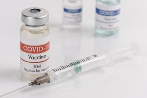 Frascos de vacina covid-19 com seringa em um fundo branco foto