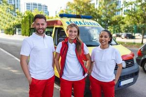 três paramédicos de a ambulância. jovem mulher e homem sorridente. médico é carregando uma médico trauma bolsa. foto