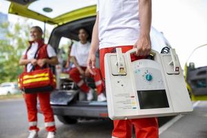 mão do a médico com desfibrilador. equipes do a emergência médico serviço estão respondendo para a tráfego acidente. foto