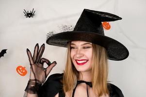 sorridente menina vestindo com festa traje mostrando OK placa. feliz dia das Bruxas conceito. truque ou tratar foto