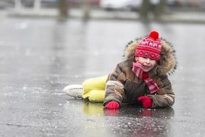 engraçado Garoto caiu baixa enquanto patinação. a criança mentiras em a gelo dentro a inverno. foto