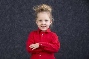 lindo pequeno Loiras menina dentro uma vermelho vestir sorridente. cinco ano velho criança. foto