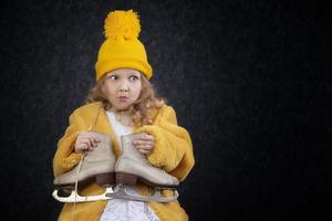 engraçado pequeno menina dentro inverno roupas com patins. foto