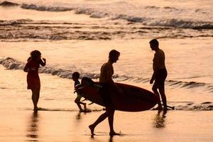 pessoas em a de praia às pôr do sol foto