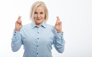 metade do comprimento retrato do lindo sonhadores Loiras vestindo azul clássico blusa em pé cruzando dela dedos com aberto olhos procurado para faço dela desejos venha verdadeiro. isolado em branco. foto