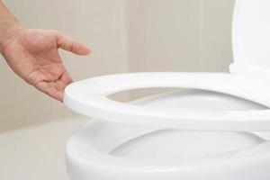 fechar acima mão do uma mulher fechamento a tampa do uma banheiro assento. higiene e saúde Cuidado conceito. foto