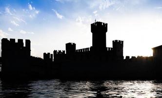 itália - silhueta do castelo sirmone no lago garda ao pôr do sol. arquitetura medieval com torre. foto