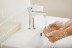 higiene. mãos de limpeza. lavar as mãos com sabão sob a torneira com água paga. foto