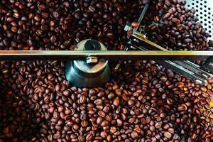 grãos de café aromáticos recém-torrados em uma moderna máquina de torrefação de café. foto