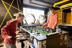 irmãos jogando mesa futebol dentro crianças jogar Centro. foto