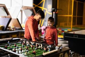 irmãos jogando mesa futebol dentro crianças jogar Centro. foto