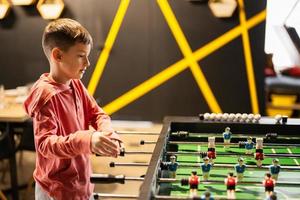 Garoto jogando mesa futebol dentro crianças jogar Centro. foto