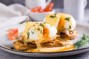 ovos Benedict e bacon em uma crocantes waffle em uma prato para caseiro café da manhã foto