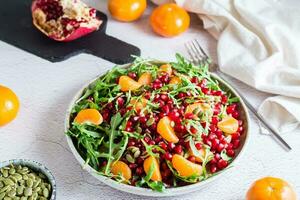 fruta Vitamina salada do romã, tangerina, Rúcula e abóbora sementes dentro uma prato em a mesa. orgânico vegetariano Comida.