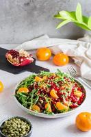 fruta Vitamina salada do romã, tangerina, Rúcula e abóbora sementes dentro uma prato em a mesa. orgânico vegetariano Comida. vertical Visão