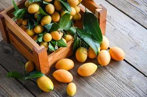 mariana ameixa fruta e folhas dentro b de madeira caixa, tropical fruta nome dentro Tailândia doce amarelo mariana ameixa maprang plango ou maionese criança foto