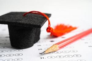 chapéu de lacuna de graduação e lápis no fundo da folha de respostas, estudo de educação, teste de aprendizagem, conceito de ensino. foto