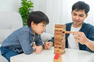 Ásia feliz solteiro pai jogando Aprendendo jogos janga com a pequeno garoto. engraçado família é feliz e animado dentro a casa. pai e filho tendo Diversão gastos Tempo junto. feriado, fim de semana, vago. foto