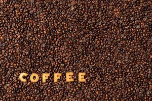 a palavra café feito com letras de biscoito em um fundo escuro de grãos de café foto