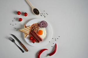 Inglês café da manhã - frito ovo, tomates e linguiça em branco fundo. topo visualizar. cópia de espaço para texto foto