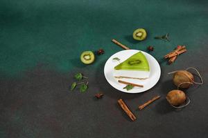 bolo de queijo com kiwi, canela bastão e folhas hortelã em uma verde fundo. cópia de cpase para texto foto