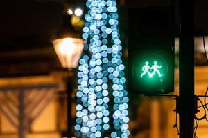 semáforo para pedestres com luz verde e luzes desfocadas da árvore de natal