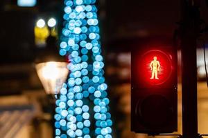 semáforo para pedestres com luz verde e luzes desfocadas da árvore de natal