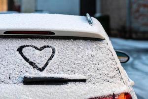 formato de coração na janela traseira de um carro coberto de neve foto