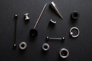 itens para um piercing de metal em fundo cinza escuro foto