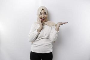 jovem ásia muçulmano mulher sorridente enquanto apontando para cópia de espaço ao lado dela foto