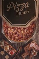 pizza com mussarela, calabresa e orégano em caixa de delivery foto
