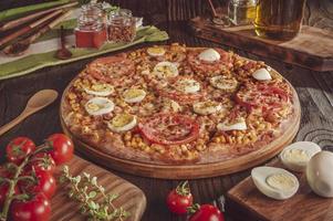 pizza brasileira com mussarela, milho, bacon, ovos, tomate e orégano foto