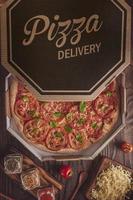 pizza brasileira com molho de tomate, mussarela, tomate, parmesão e manjericão em caixa de delivery foto