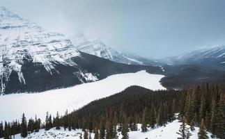 cenário do peito lago com neve coberto dentro a vale em nevando dia às banff nacional parque foto