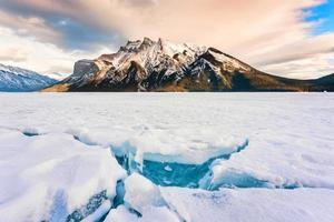 congeladas lago minnewanka com rochoso montanhas e rachado gelo a partir de a lago dentro inverno às banff nacional parque foto