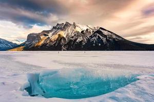 congeladas lago minnewanka com rochoso montanhas e rachado gelo a partir de a lago dentro inverno às banff nacional parque foto