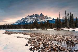 nascer do sol sobre castelo montanha sobre arco rio dentro inverno às banff nacional parque foto