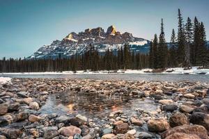 nascer do sol sobre castelo montanha sobre arco rio dentro inverno às banff nacional parque foto