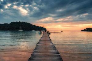 pôr do sol sobre de madeira cais e barco dentro tropical mar às koh kood ilha foto